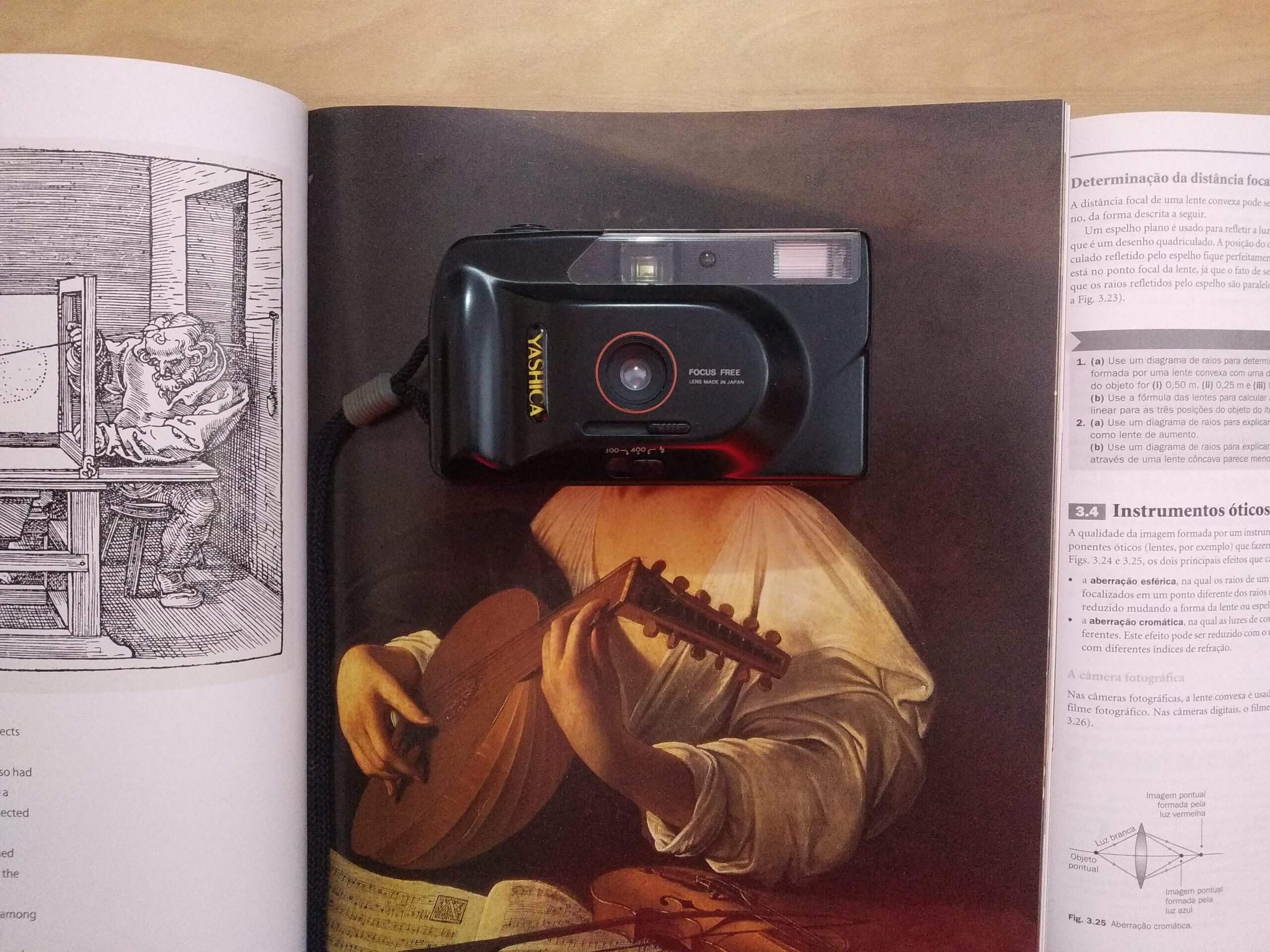Câmera fotográfica em cima de livro.